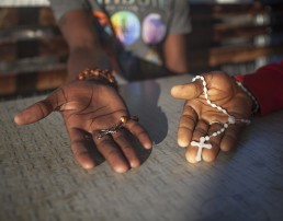 Zang and DHL from Cameroon and residents at the Moria camp in Lesbos are showing their crucifix as a symbol of their faith.